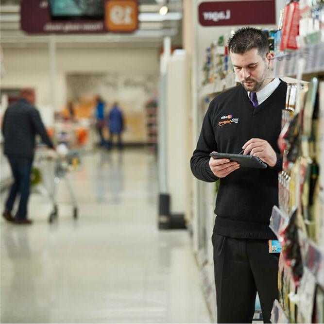 A Mitie security guard in a Sainsbury's store using a mobile reporting device