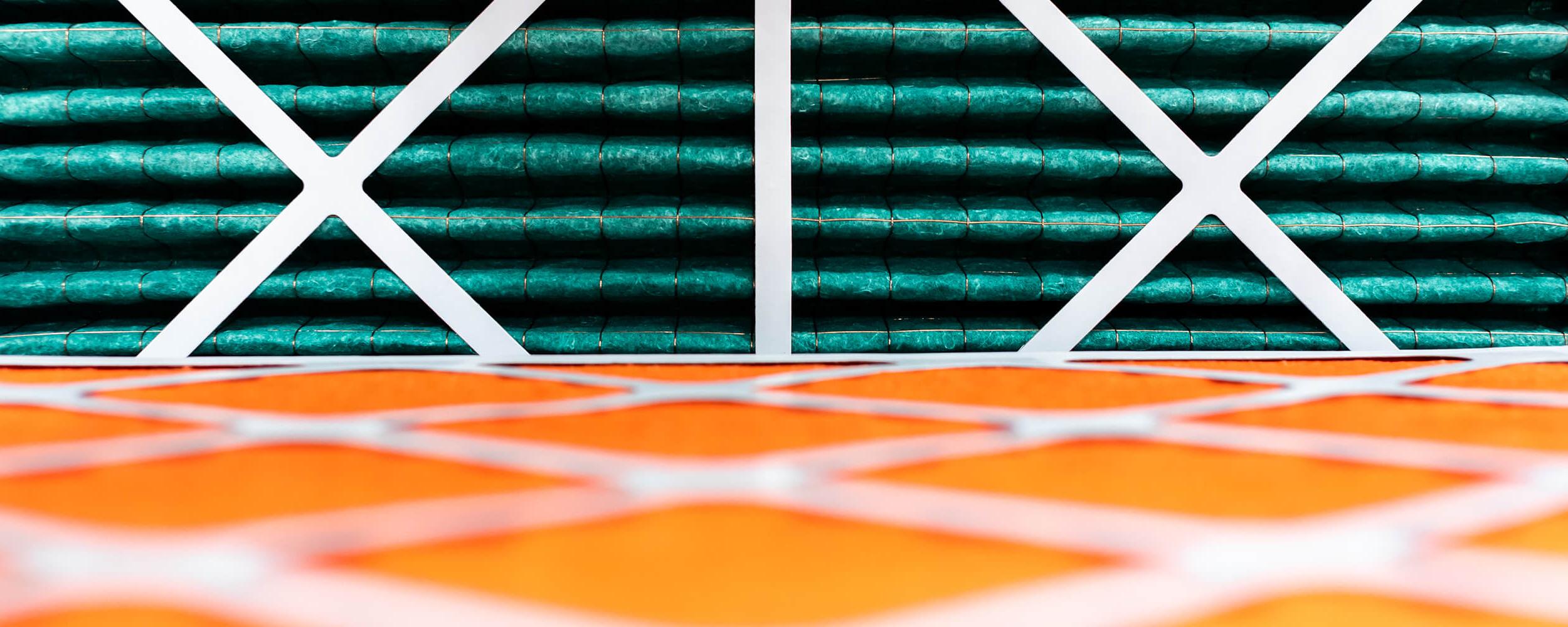 关闭-up photography of rolls of orange and green insulating material being held in place with white cross frames
